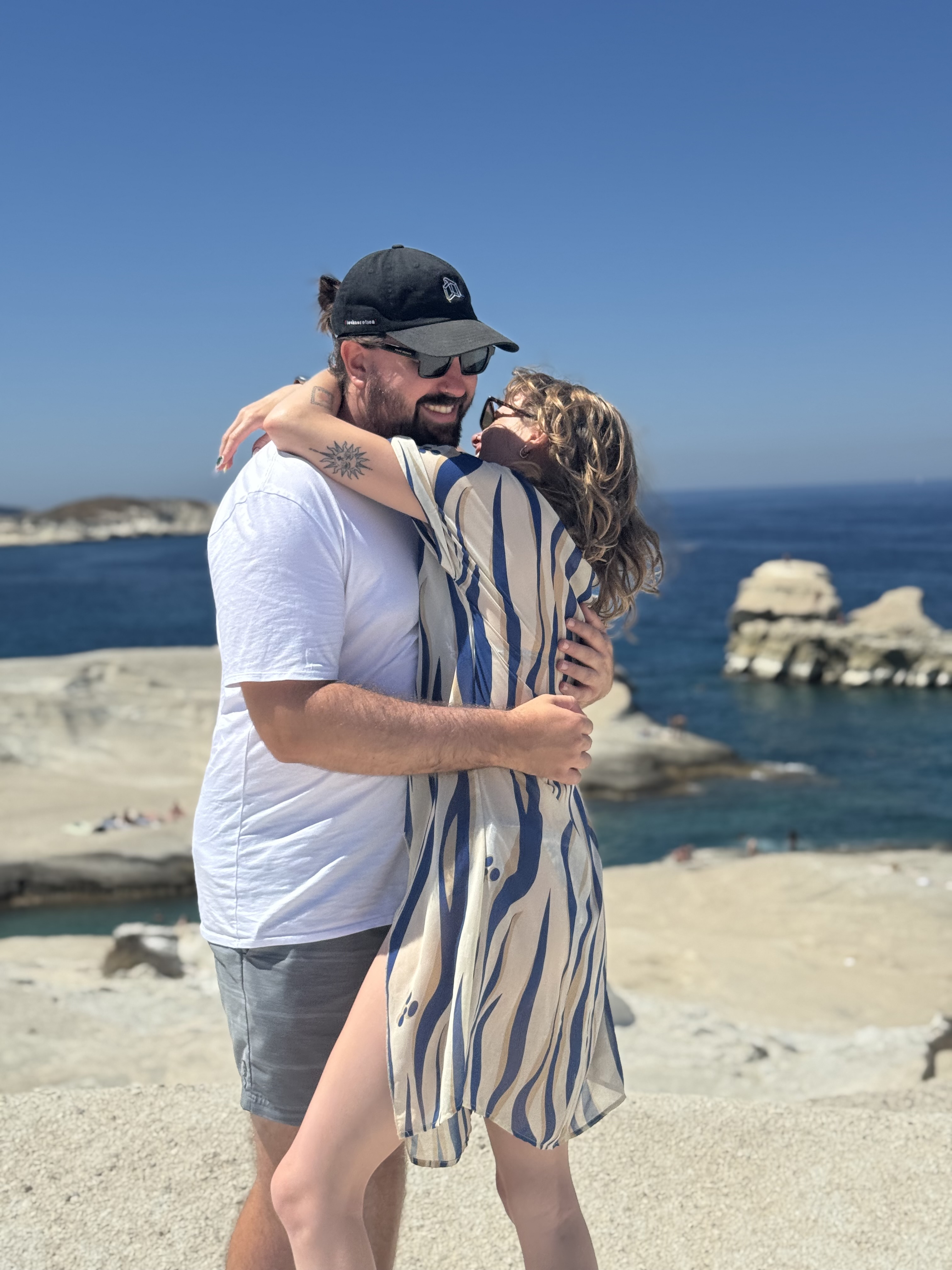 Chris and Paige hugging by the coast